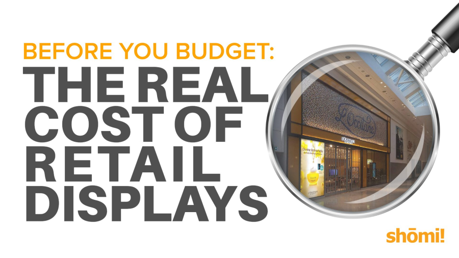 A graphic with the text Before you budget: The real cost of retail displays beside a magnifying glass focusing on a retail store entrance. The shomi! logo is in the lower right corner.