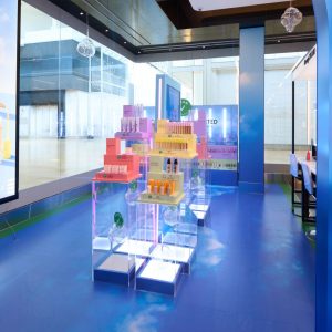 A Sephora pop-up display with colorful, tiered stands of skincare and makeup products set on a blue floor in a shopping mall.
