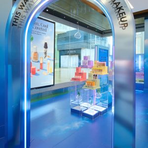 An arched doorway with the text This Way to Clean at Sephora Makeup frames a retail display of skincare products on tiered clear platforms.